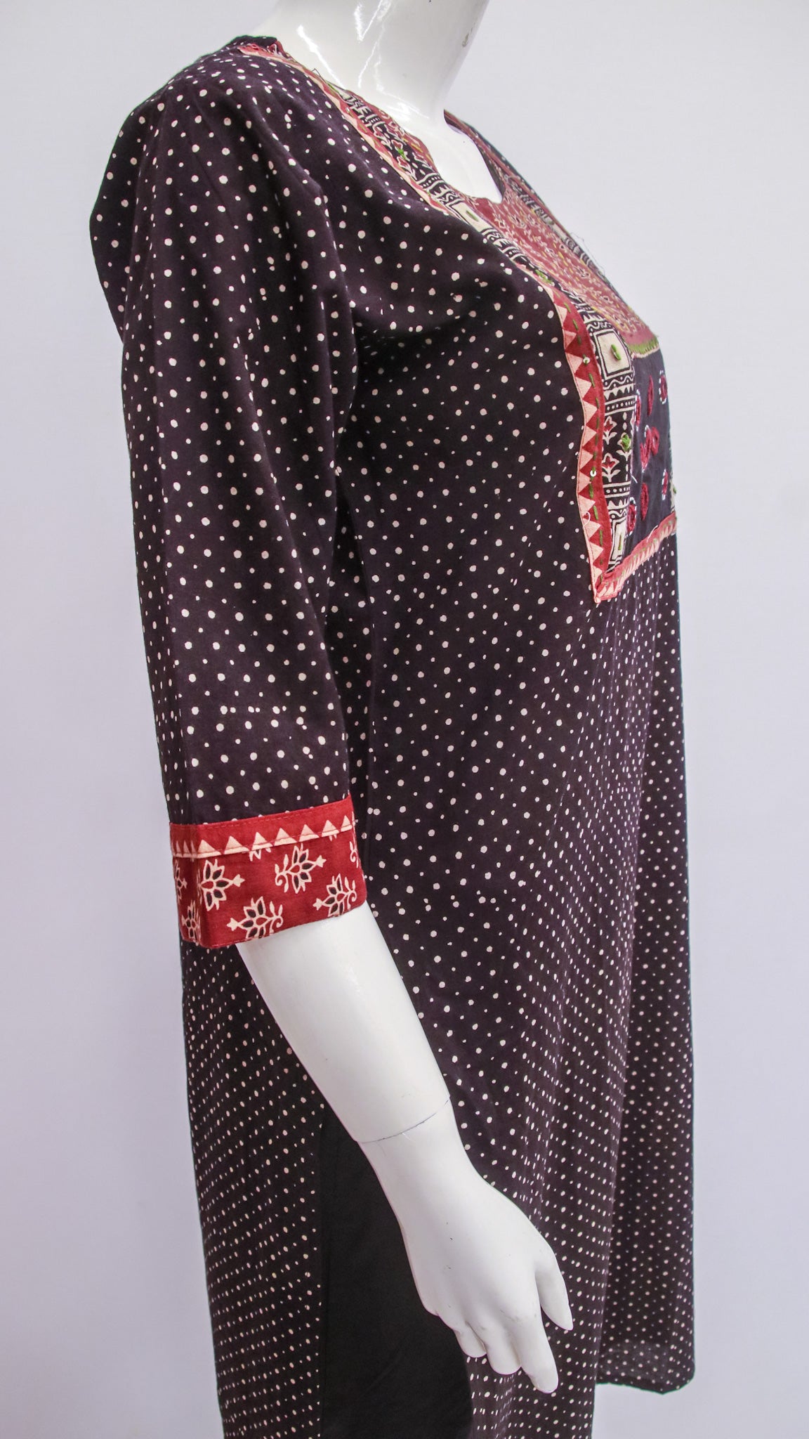 Black patterned dress with red accents on a mannequin against a white background