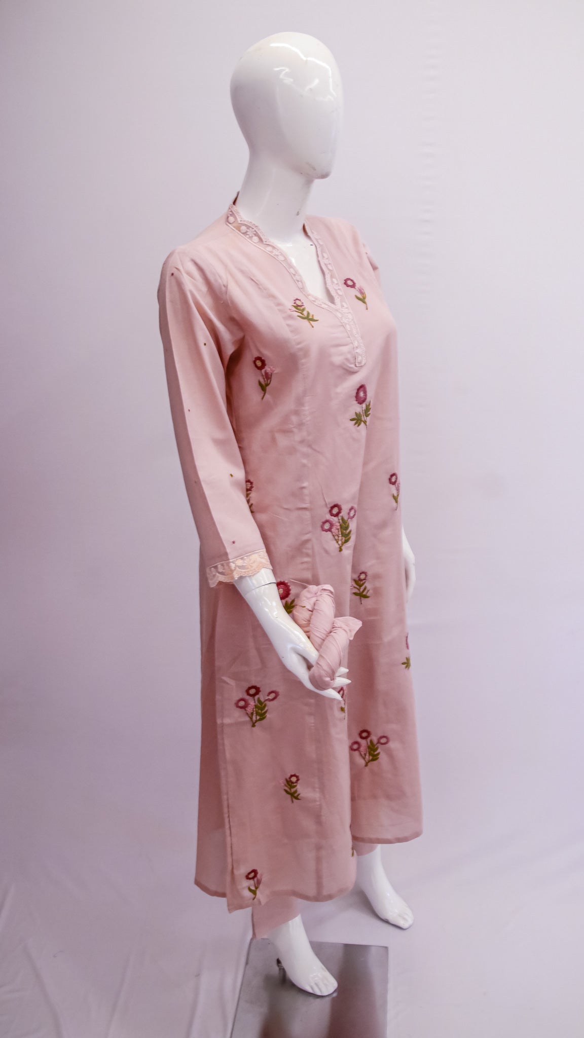 Pink embroidered dress on a mannequin against a white background