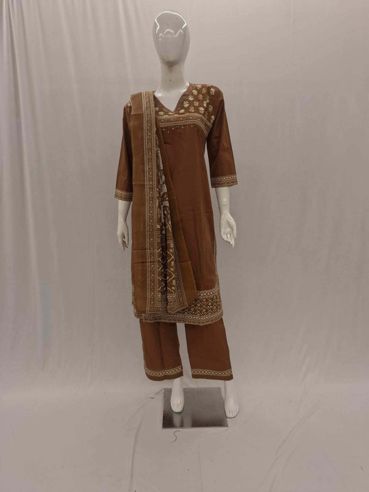 Brown traditional outfit with a saree on a mannequin against a white background
