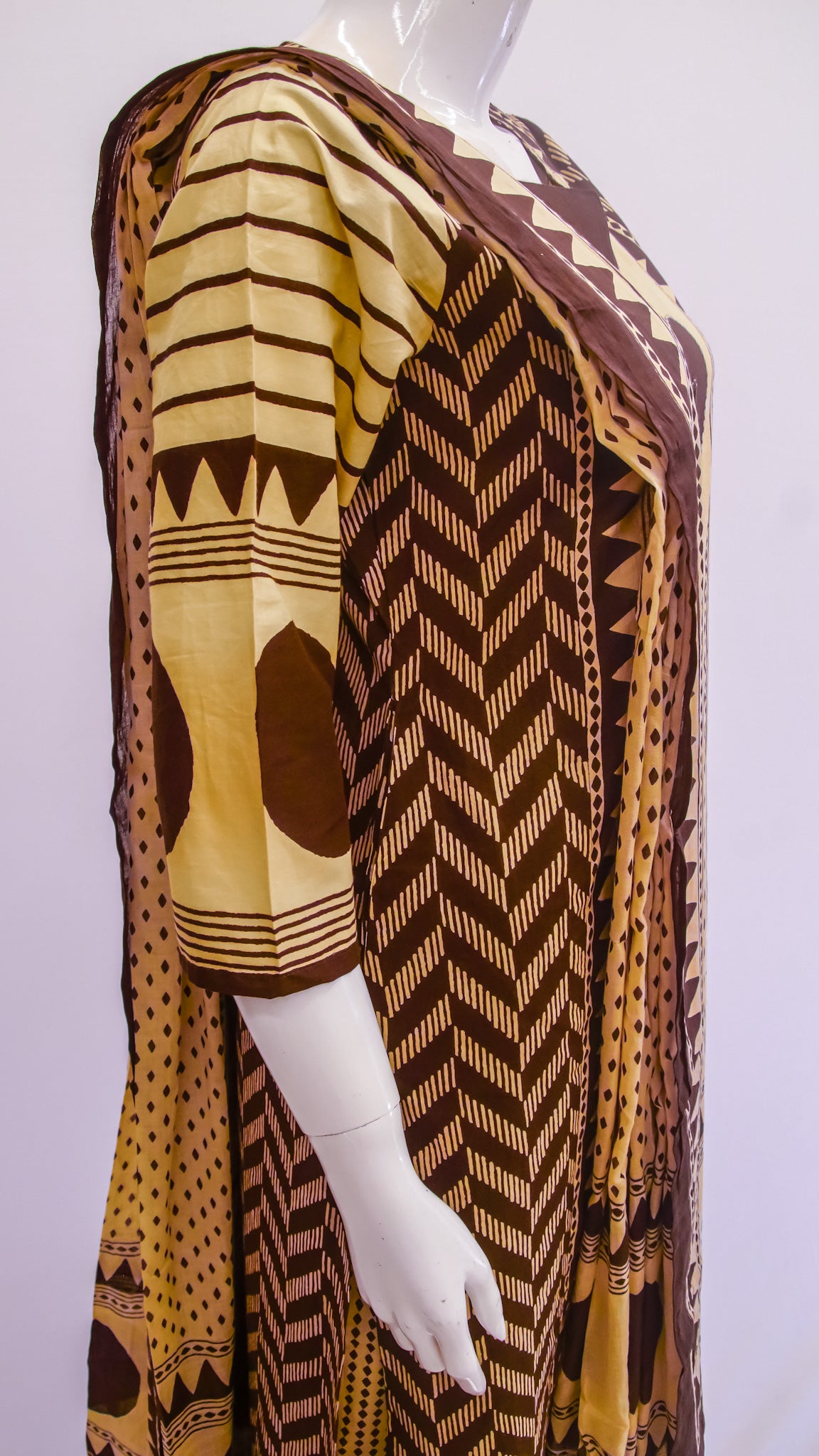 Mannequin wearing a patterned brown and yellow garment on a white background
