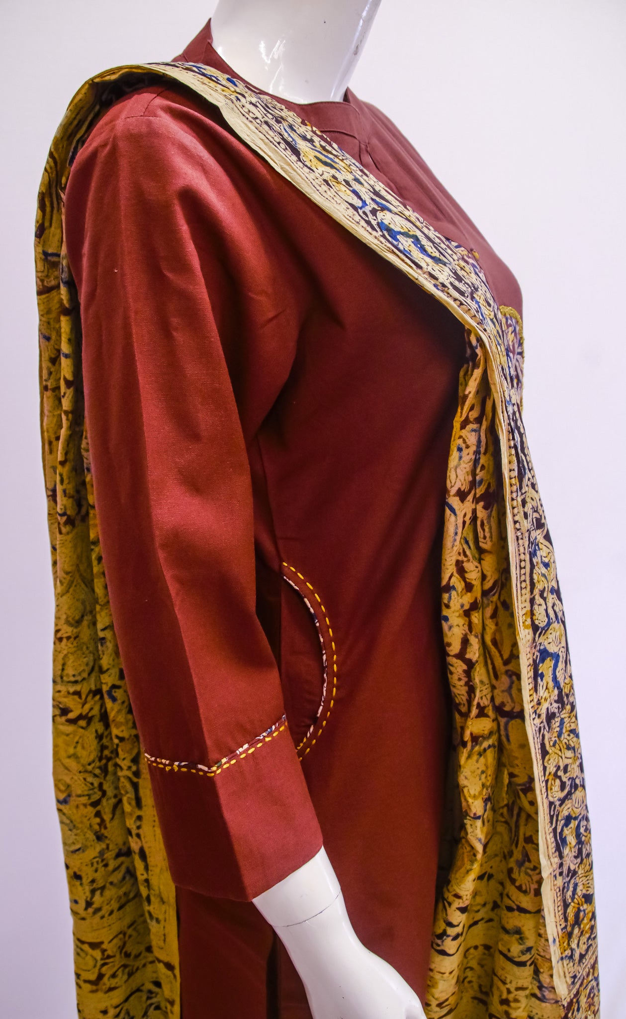 Red traditional outfit with gold and yellow patterns on a mannequin against a white background