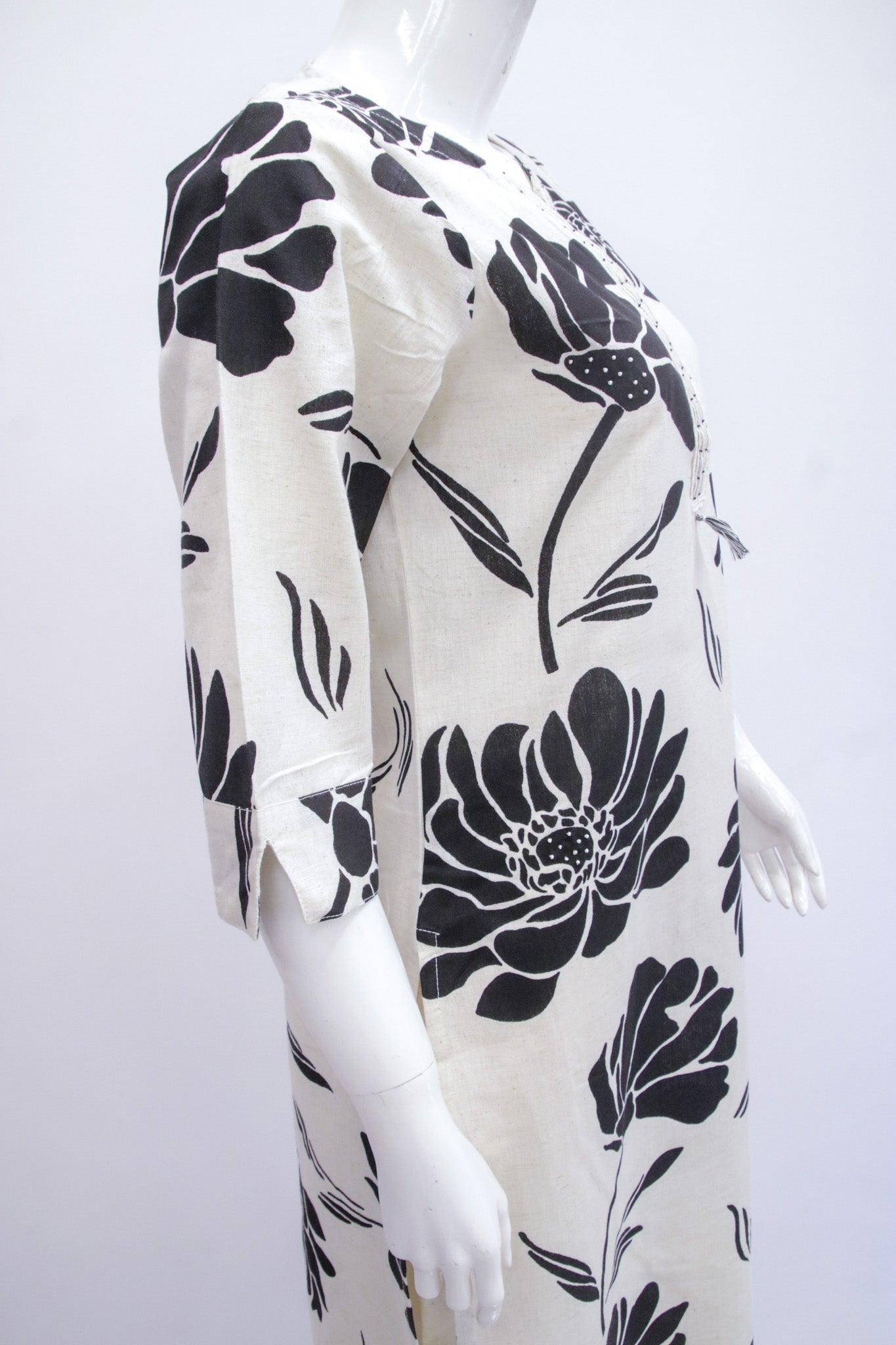 Mannequin wearing a white dress with black floral patterns on a white background