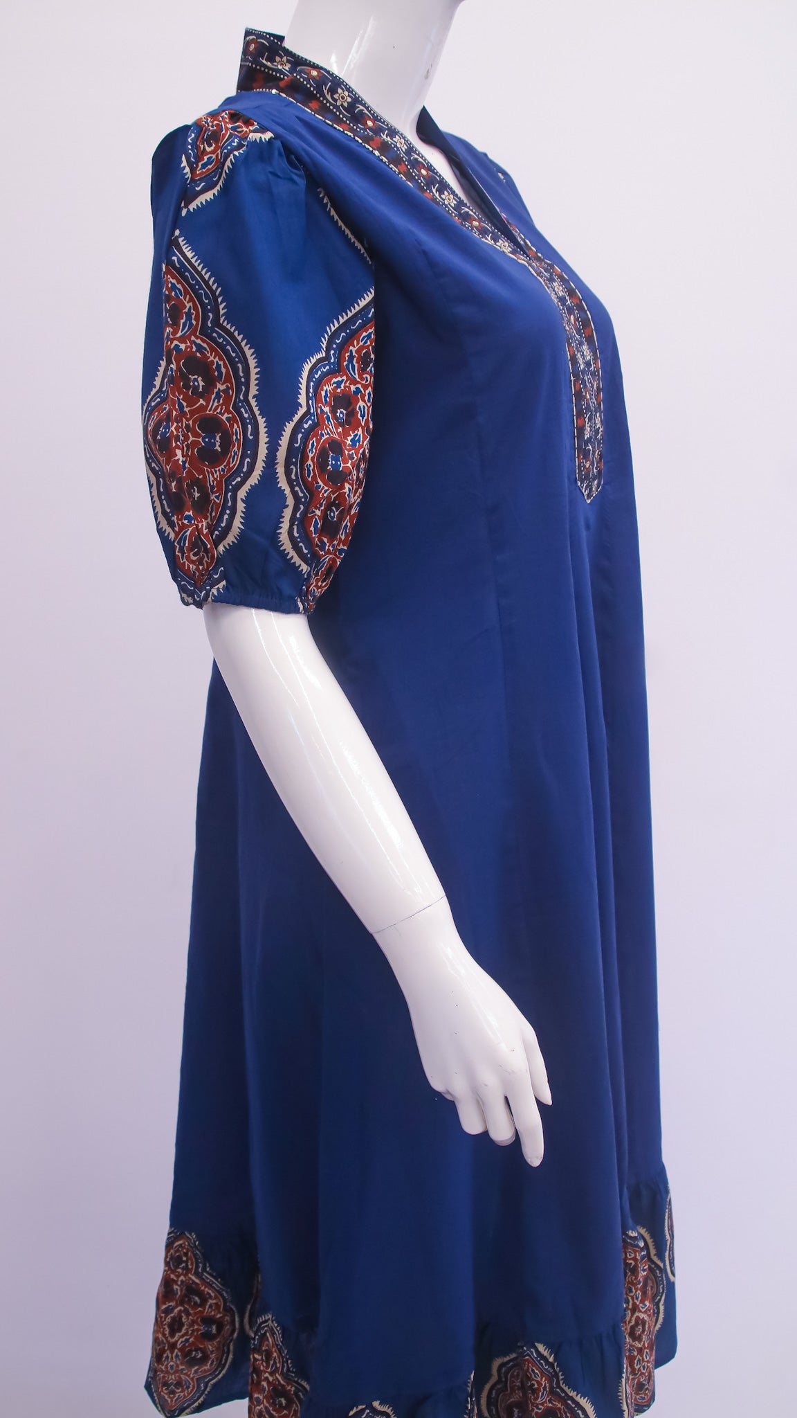Blue dress with patterned sleeves on a mannequin against a white background