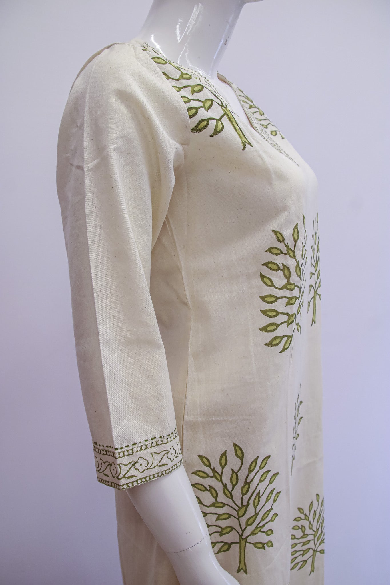 White blouse with green leaf patterns on a mannequin against a white background