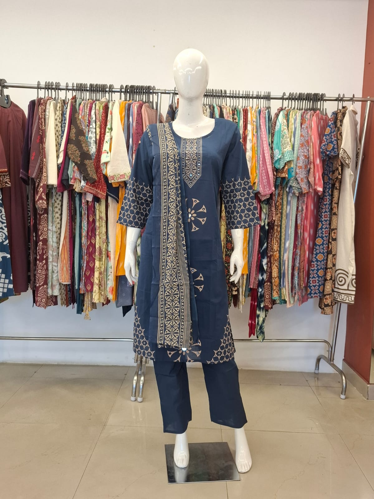 Mannequin wearing a blue embroidered outfit in a clothing store.