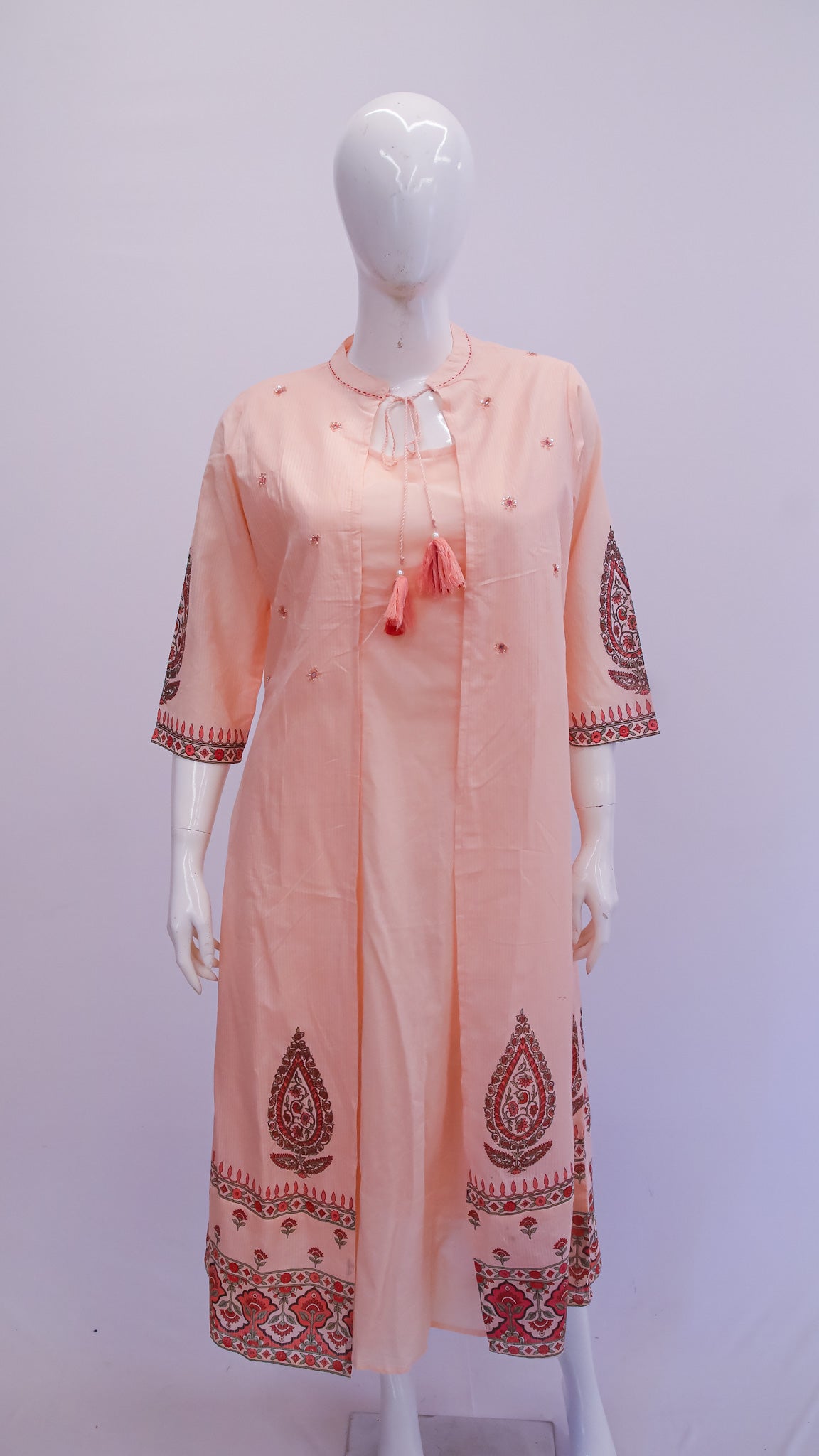 Peach-colored kurta with intricate patterns on a mannequin against a white background