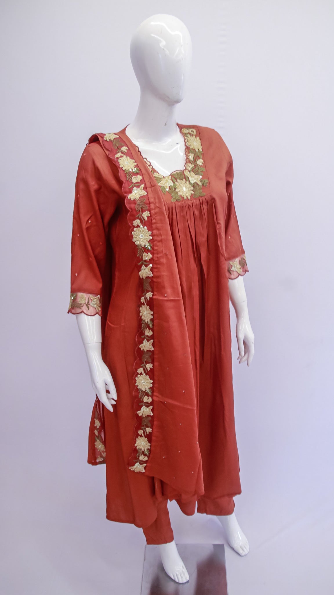 Red embroidered dress on a mannequin against a white background