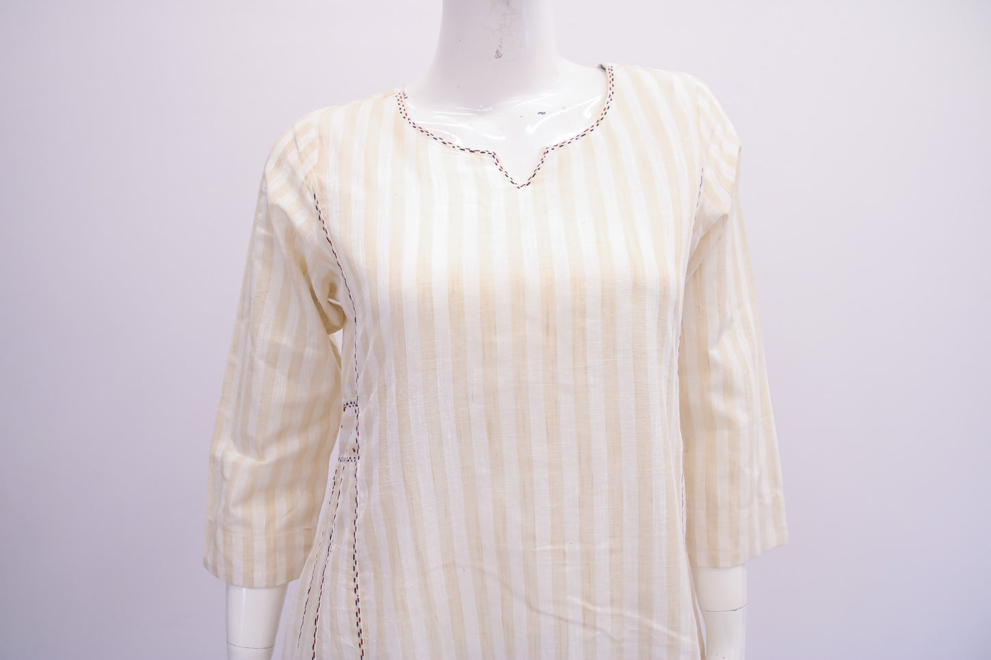 White blouse with gold stripes on a mannequin against a white background