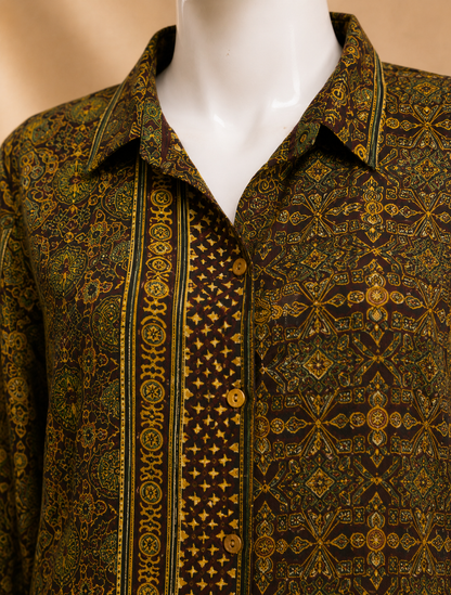A close-up of a patterned button-up shirt displayed on a white mannequin torso. The shirt features an intricate dark brown and olive green geometric and floral print with vertical decorative stripes and gold-toned buttons.