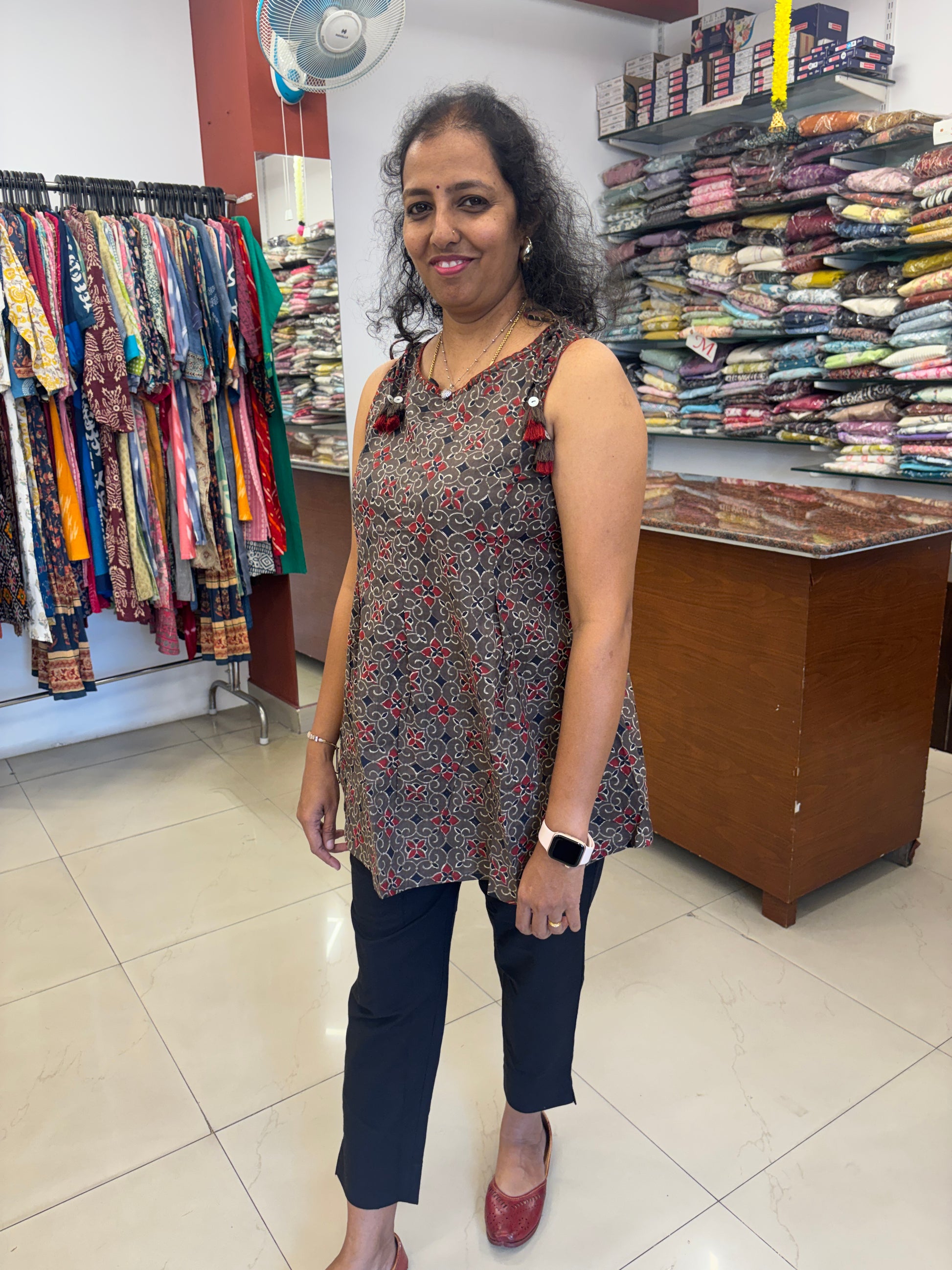 Woman standing in a room with shelves filled with books and fabrics.