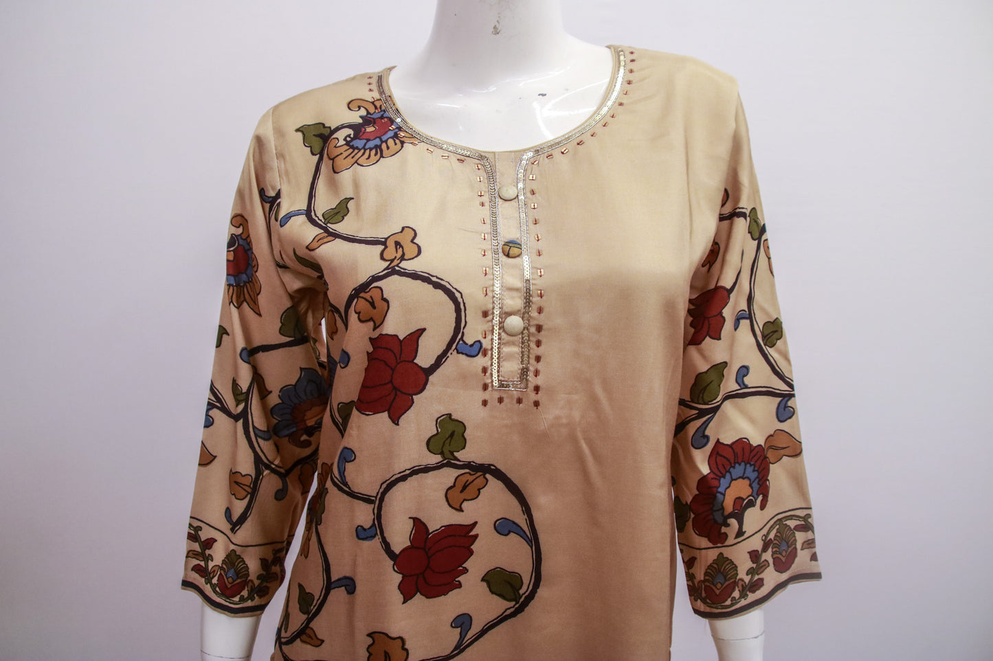 Beige blouse with floral embroidery on a mannequin against a white background