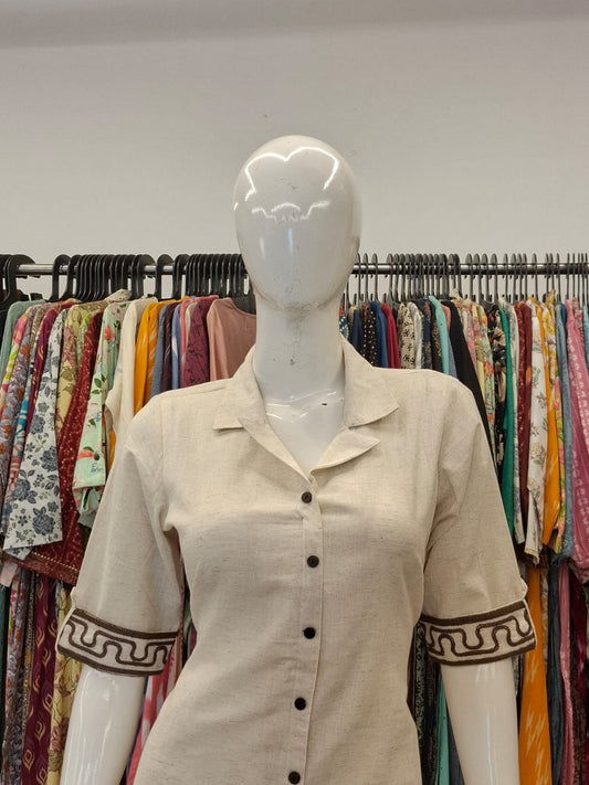 Mannequin wearing a beige shirt with decorative sleeves in a clothing store.