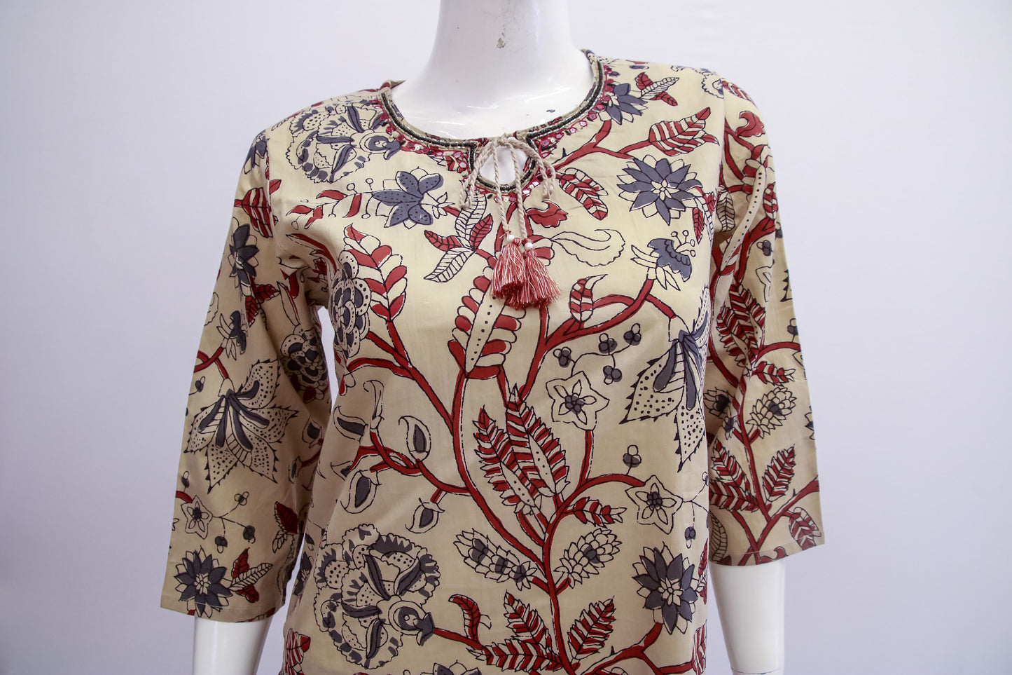 Mannequin wearing a patterned blouse with floral and abstract designs on a white background