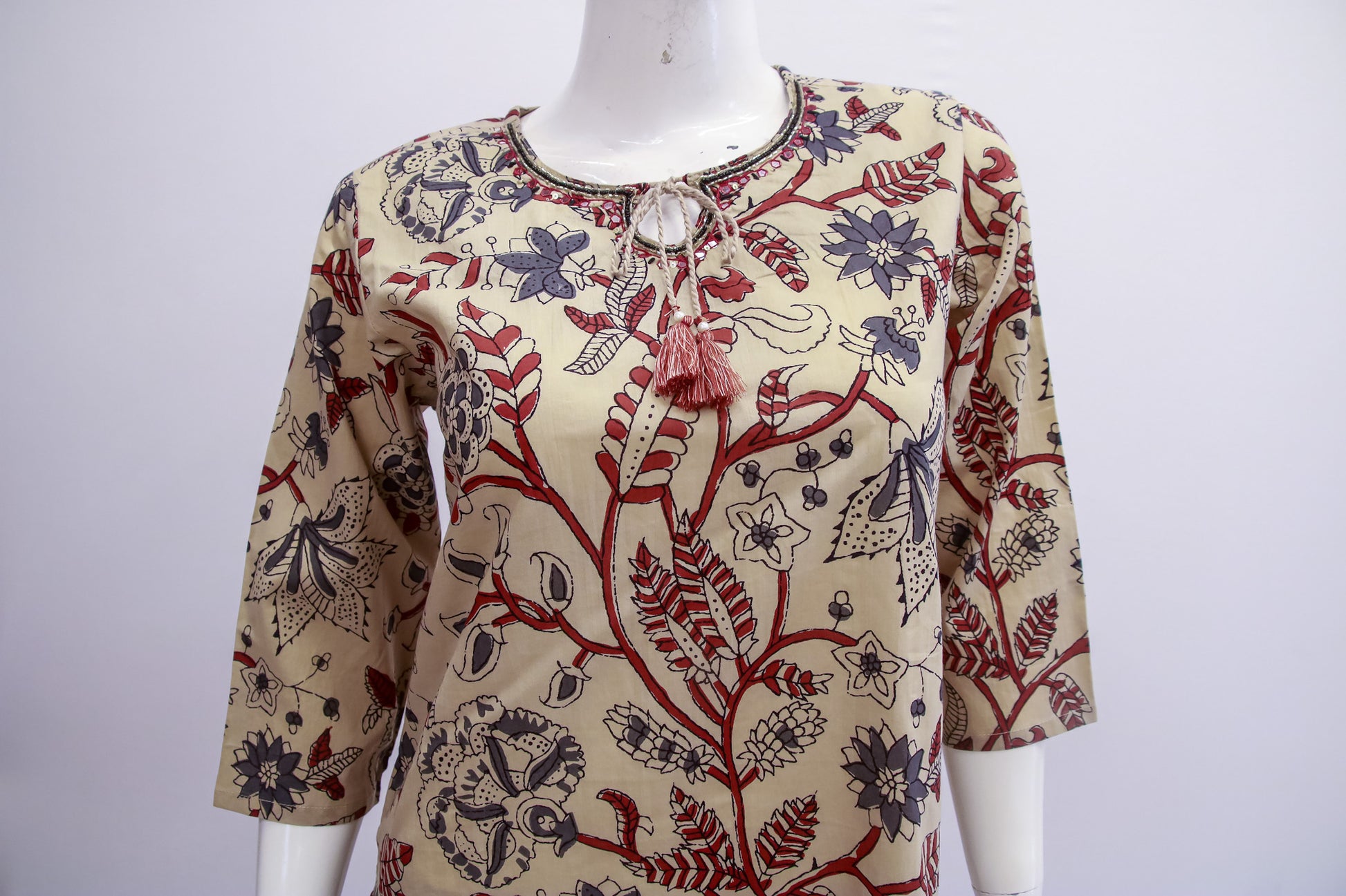 Mannequin wearing a patterned blouse with floral and abstract designs on a white background