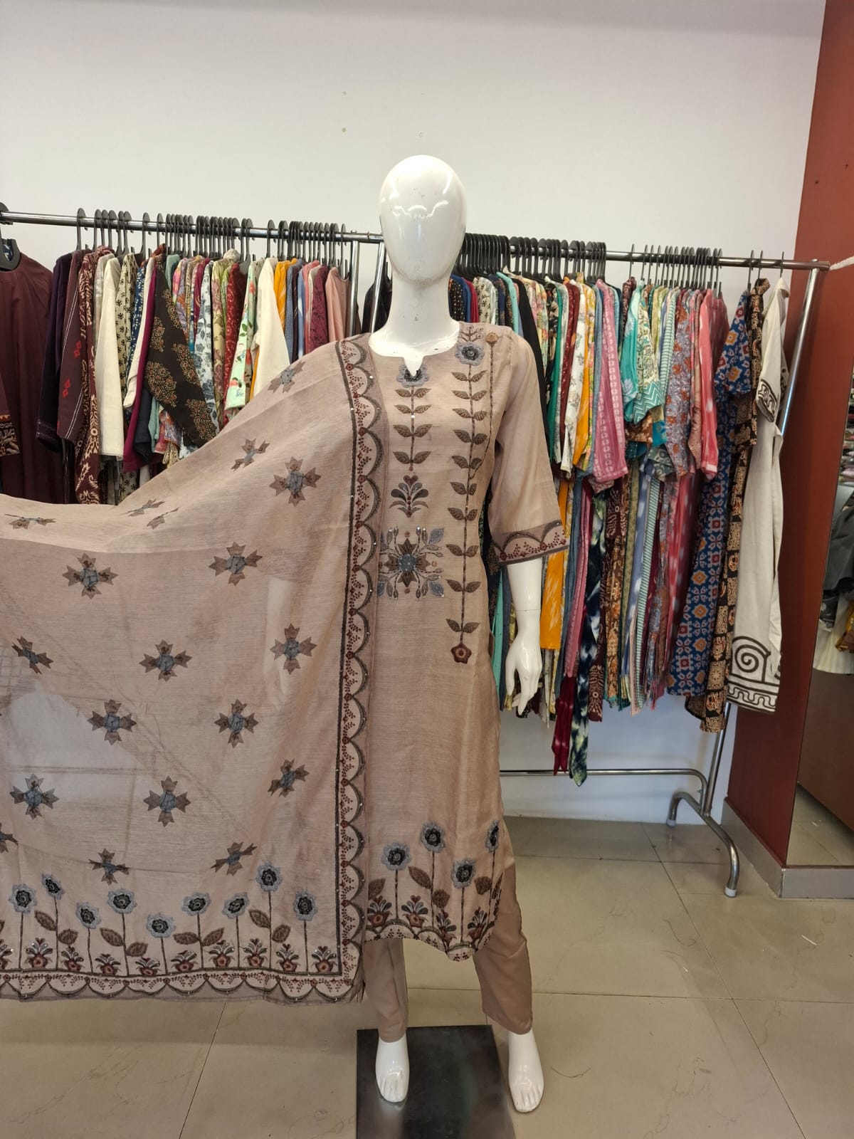 Mannequin wearing a brown embroidered outfit with a matching dupatta in a clothing store.