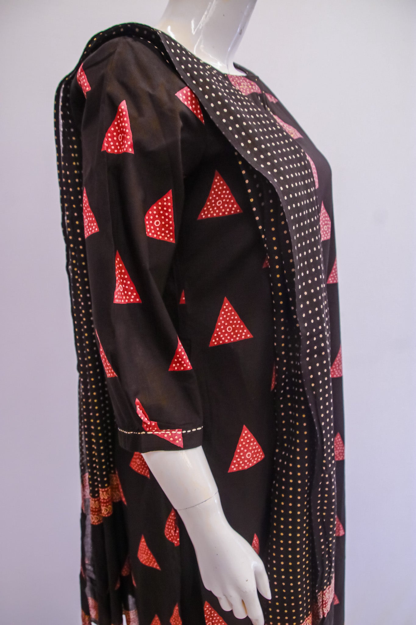Mannequin wearing a black dress with red triangle patterns on a white background
