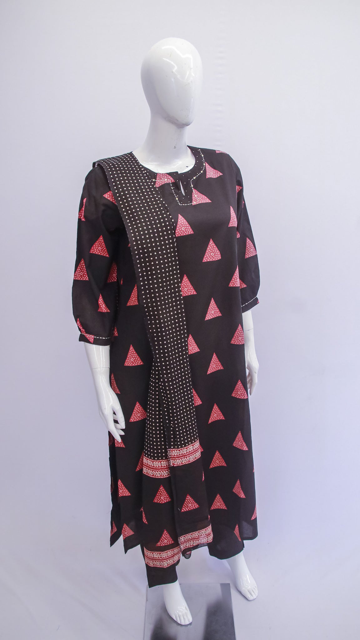 Mannequin wearing a black dress with pink triangle patterns on a white background