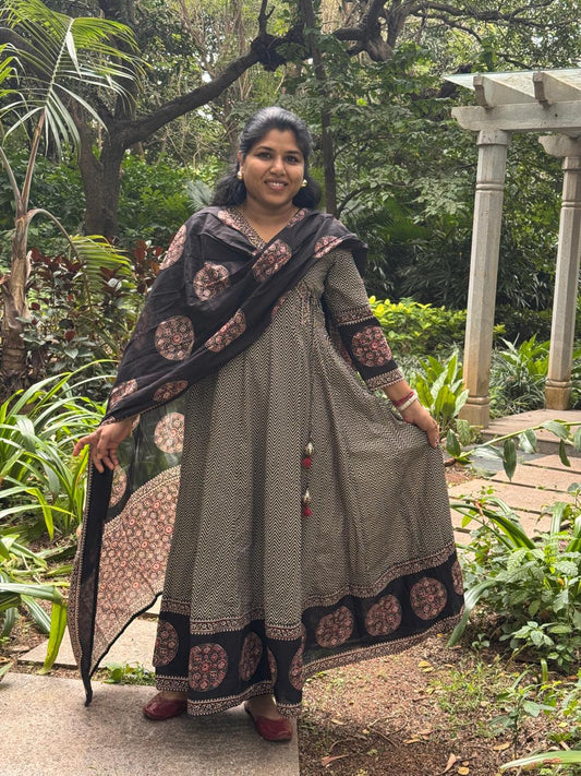 Woman in traditional attire standing outdoors in a garden setting