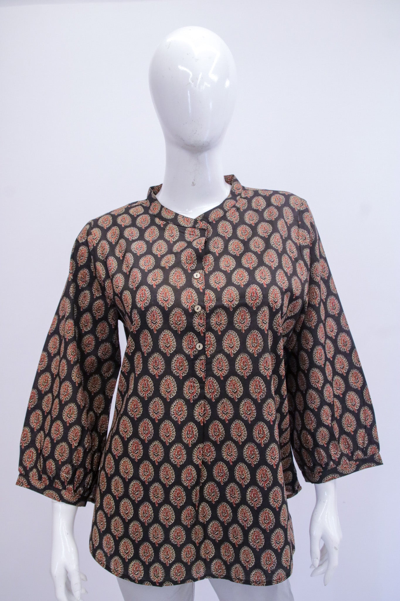Mannequin wearing a patterned brown and black top on a white background