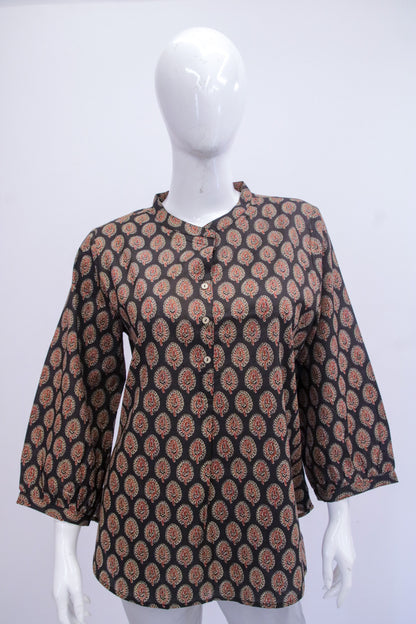 Mannequin wearing a patterned brown and black top on a white background