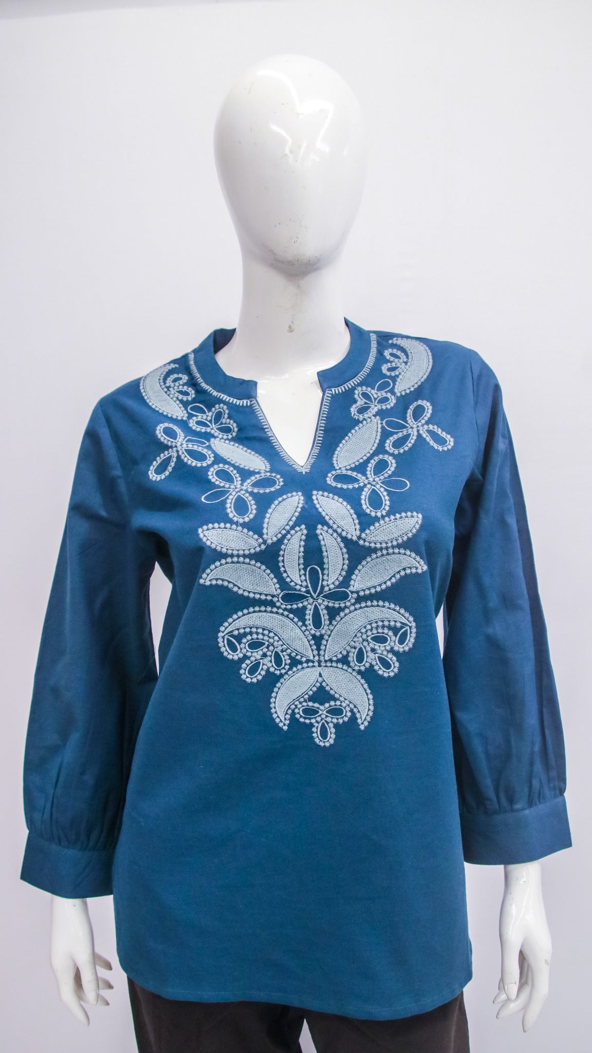 Blue embroidered blouse on a mannequin against a white background