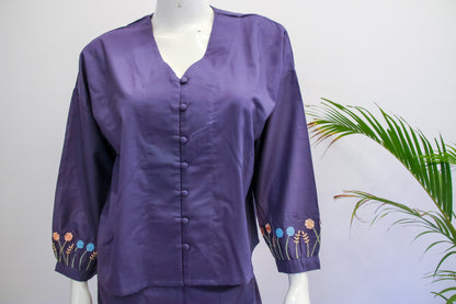 Purple blouse with floral embroidery on a mannequin against a white background