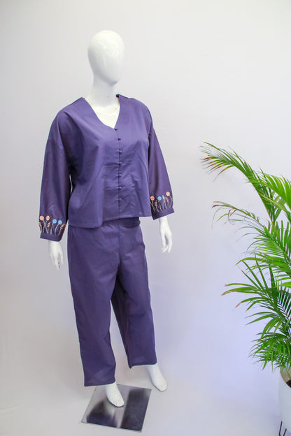Purple scrub set on a mannequin against a white background with a plant to the side.