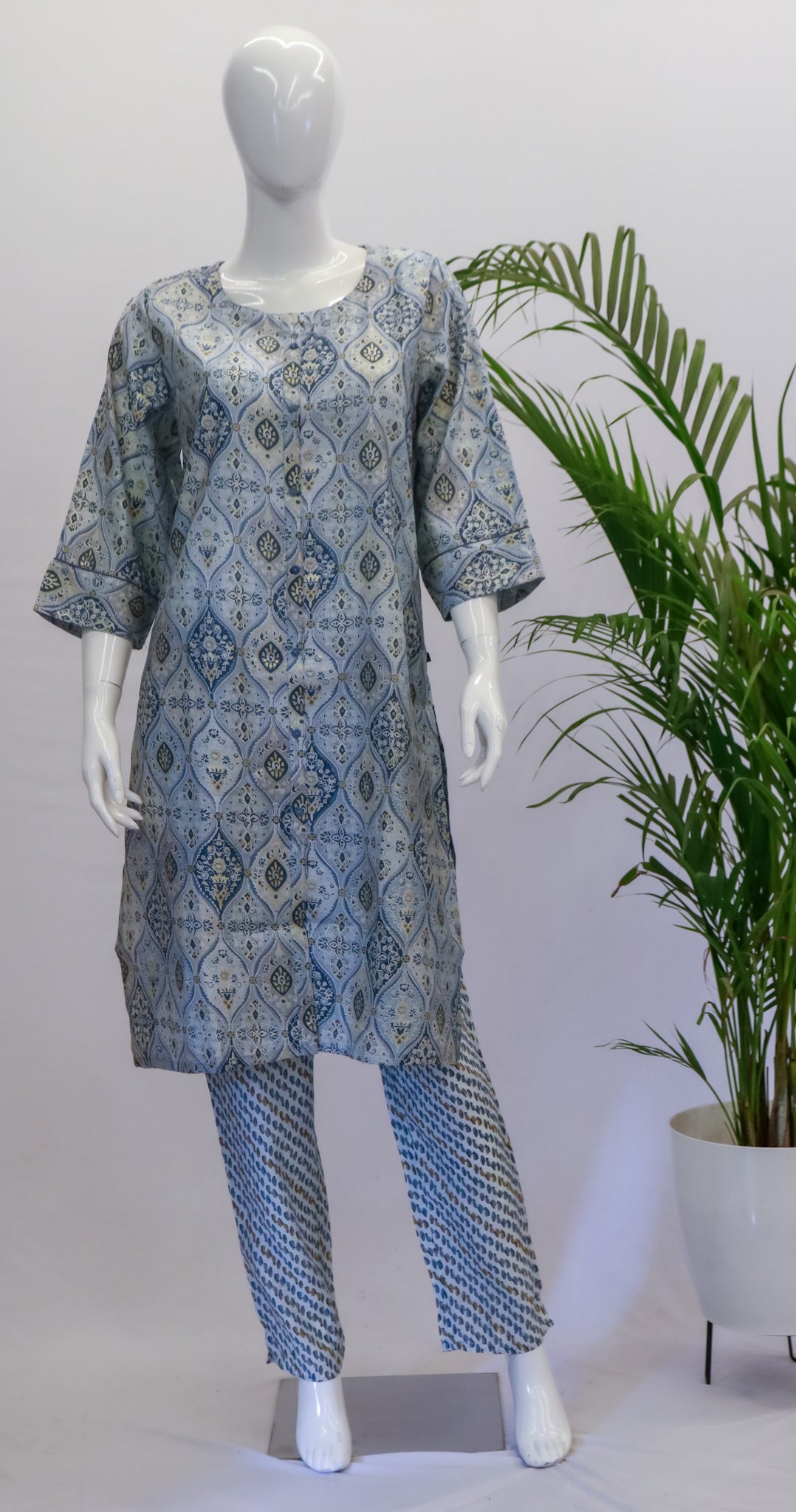 A mannequin displaying a blue muslin dupatta set with a floral pattern, consisting of a kurta, pant, and dupatta, standing in a retail setting.