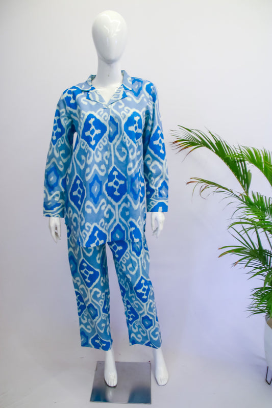Blue patterned onesie on a mannequin against a white background with a plant to the side.