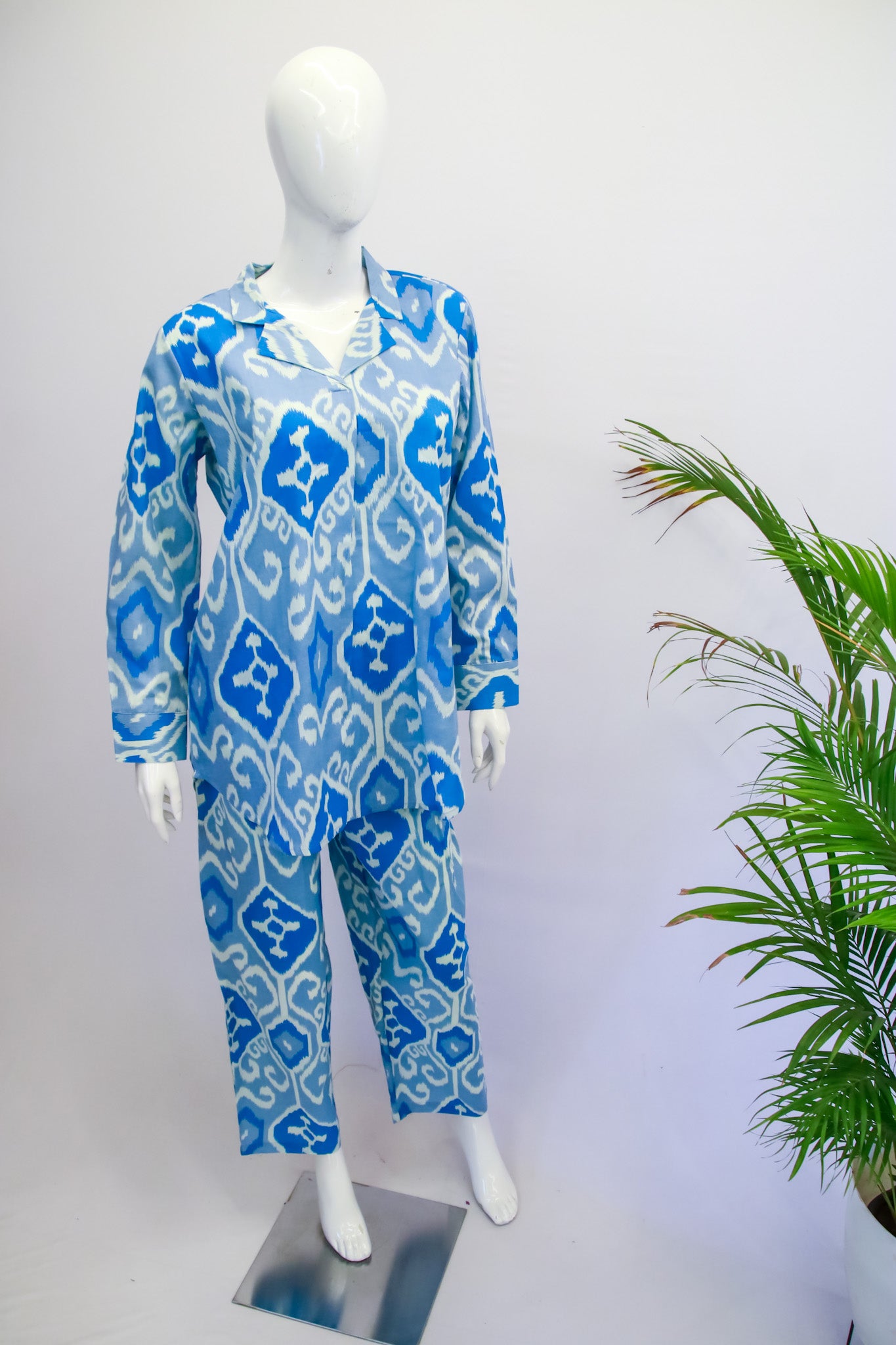 Mannequin wearing a blue and white patterned outfit with a plant in the background
