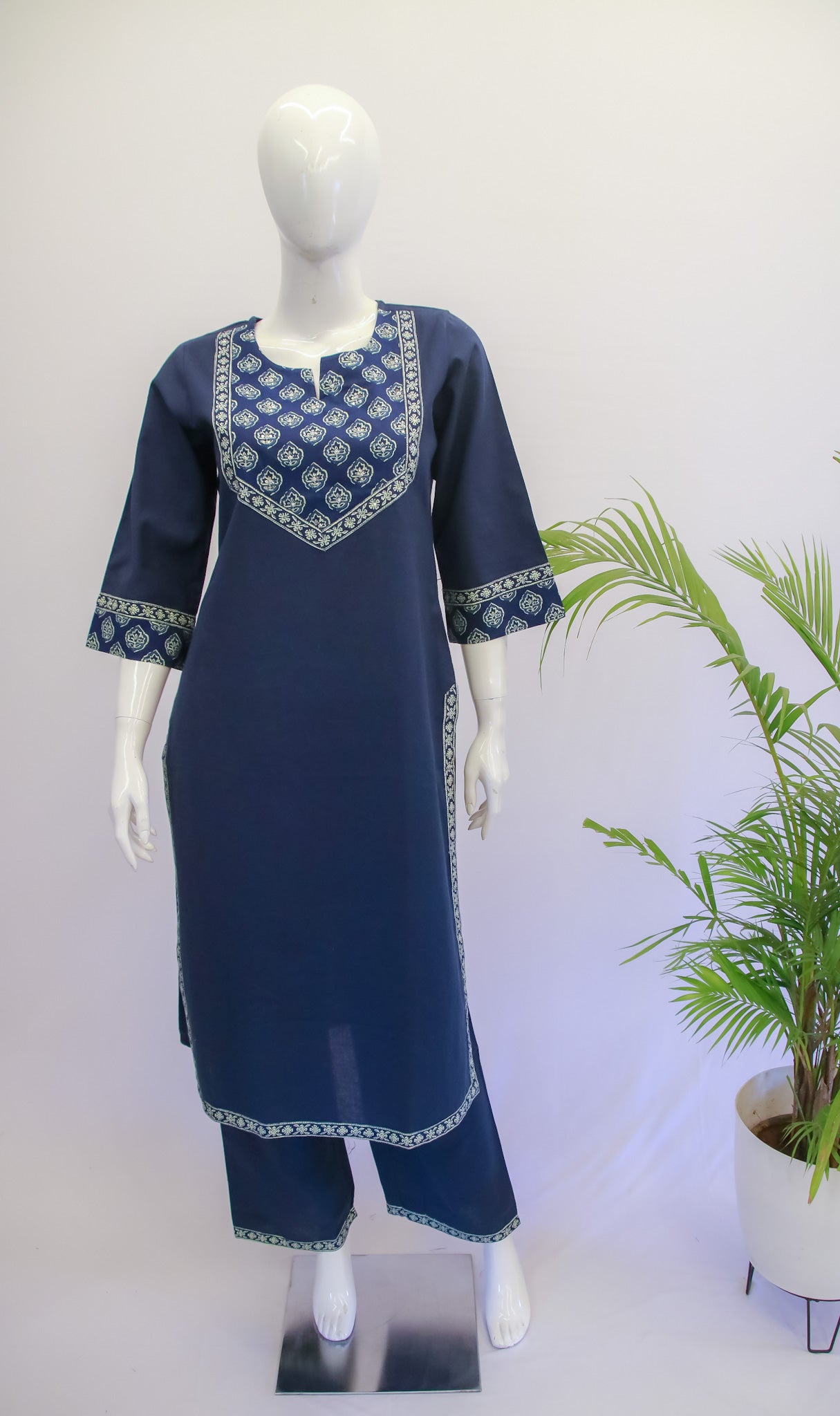 A mannequin displaying a blue color top and pant set with floral prints and applique work on the kurta.