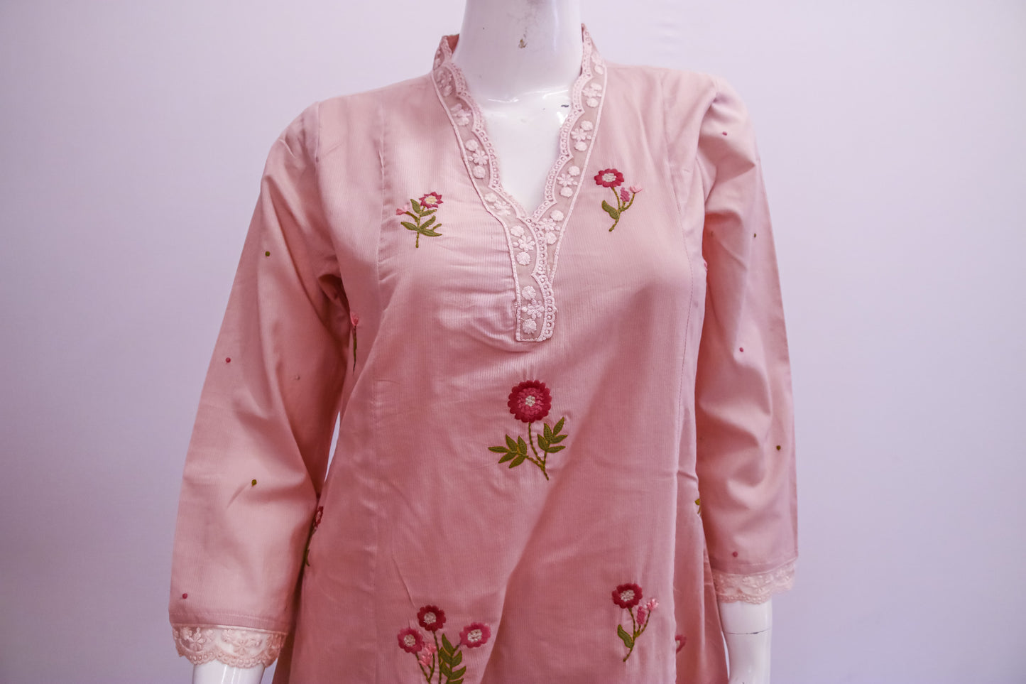 Pink embroidered dress on a mannequin against a white background