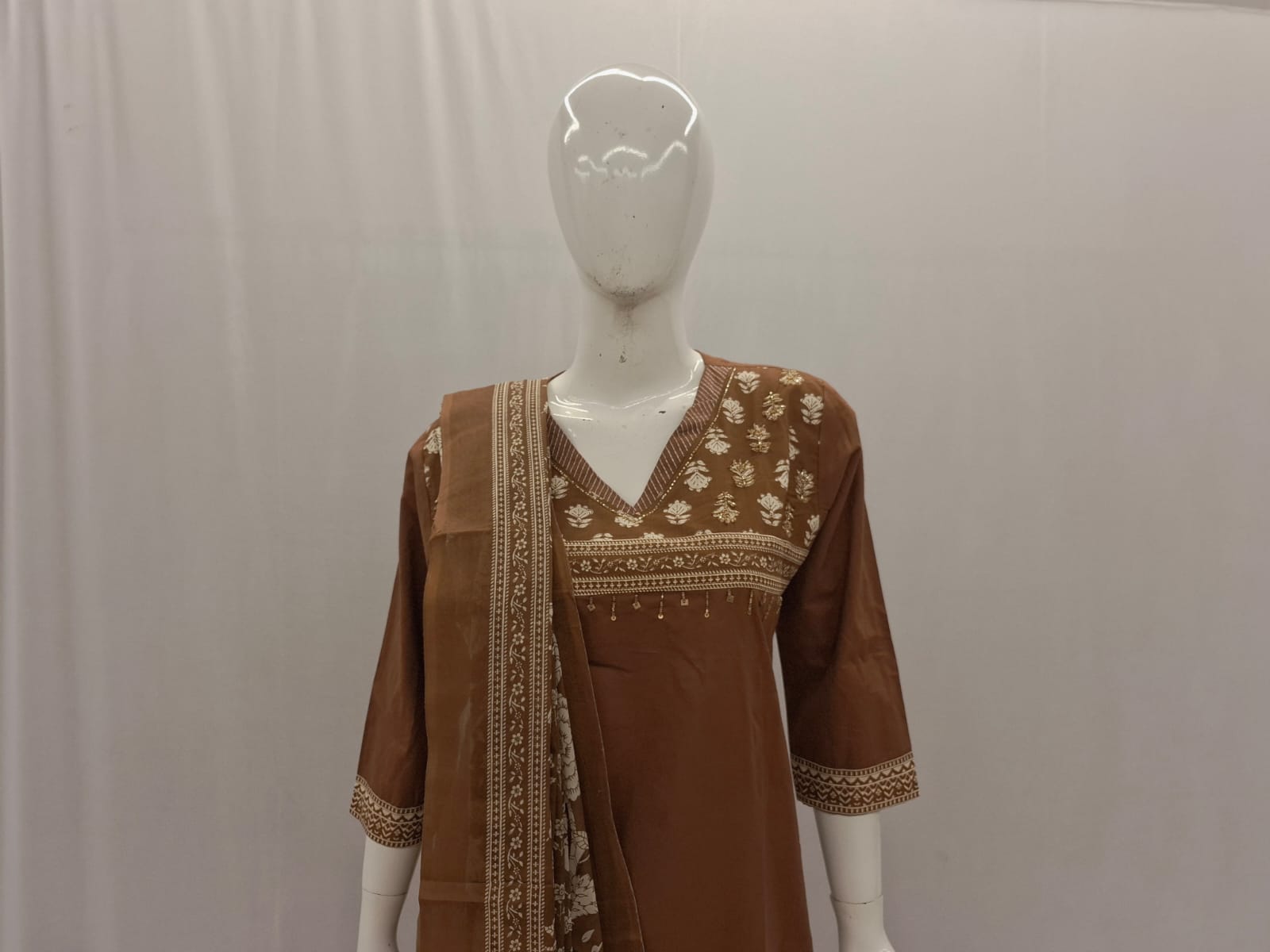 Brown embroidered outfit on a mannequin against a plain background