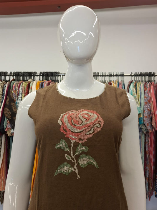 Mannequin wearing a brown sleeveless top with a rose design in a clothing store.
