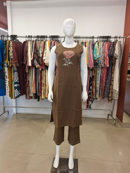 Mannequin wearing a brown dress with floral embroidery in a clothing store.