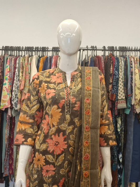 Mannequin wearing a floral dress with a colorful background of clothing racks.
