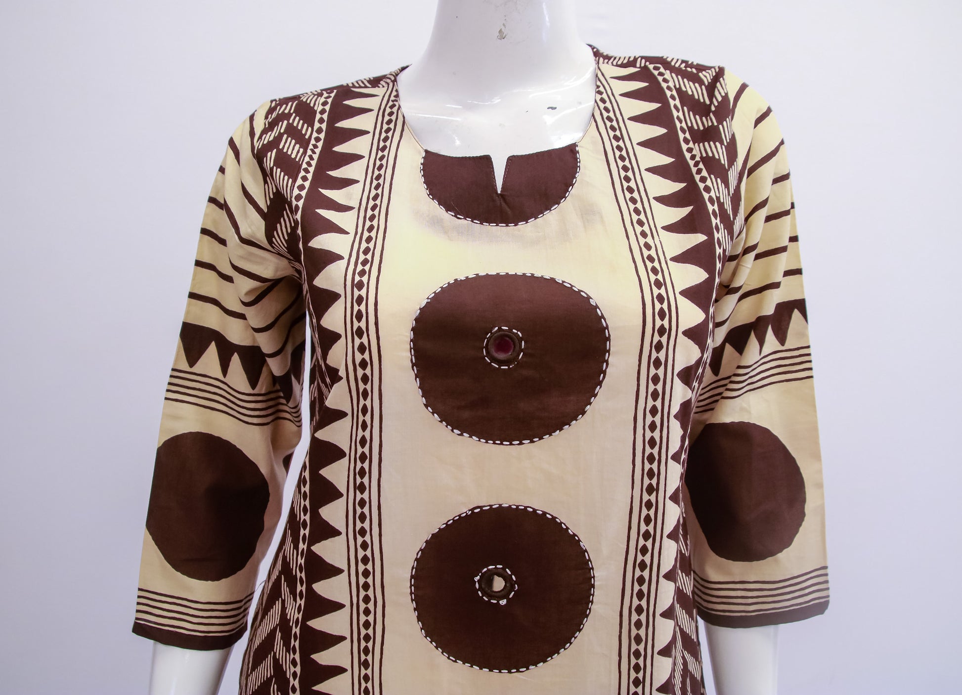 Mannequin wearing a patterned top with brown and beige design on a white background