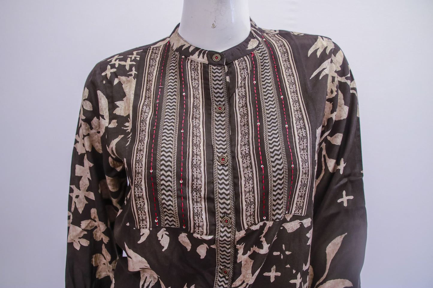 Mannequin wearing a patterned shirt with a brown and beige design on a white background