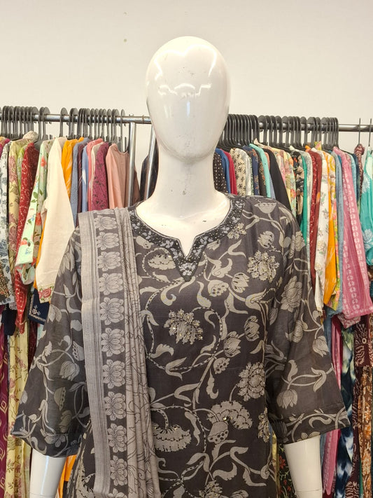 Mannequin wearing a floral dress with a colorful background of hanging clothes
