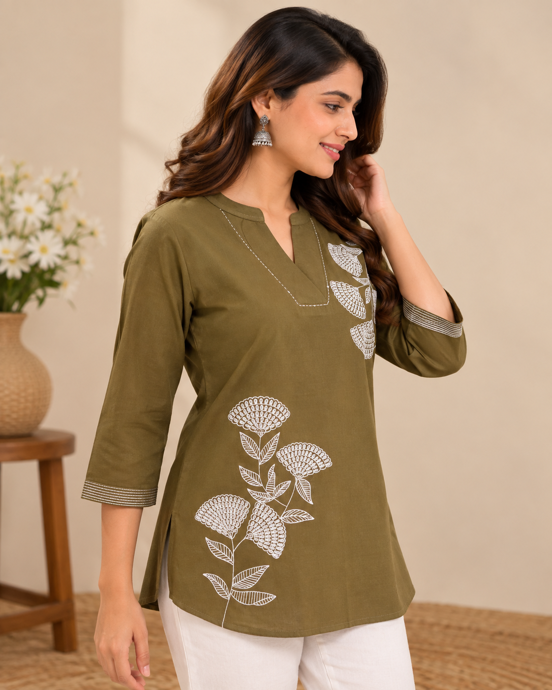 Olive green embroidered short kurti with white floral embroidery, V-neckline, three-quarter sleeves and striped cuff detailing, styled on a female model