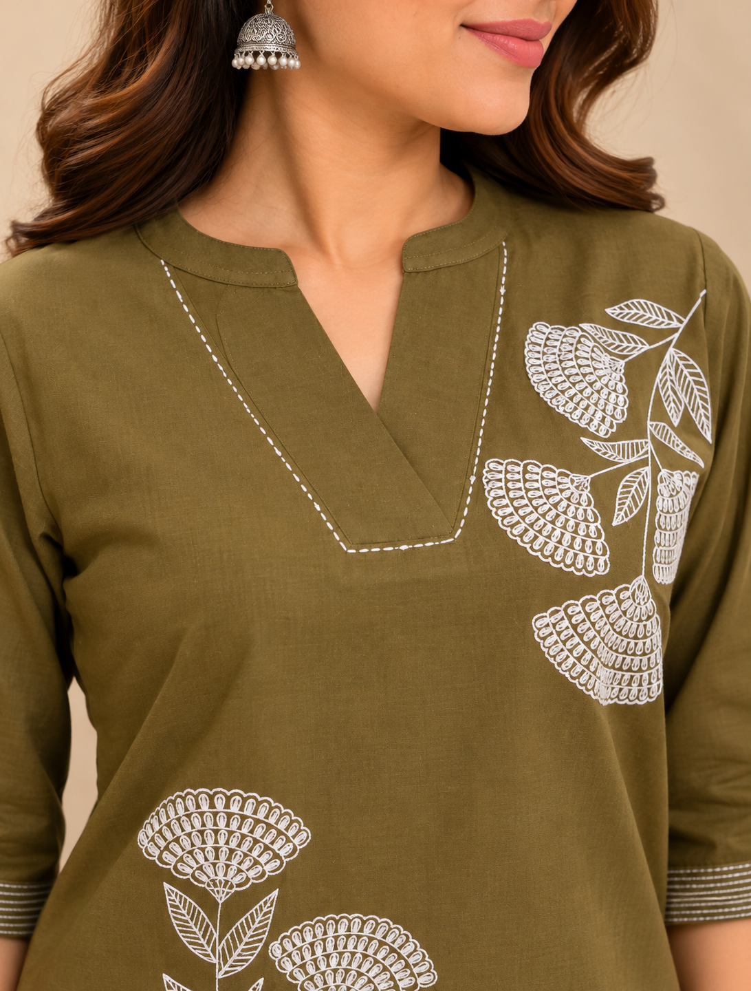 Olive green embroidered short kurti with white floral embroidery, V-neckline, three-quarter sleeves and striped cuff detailing, styled on a female model