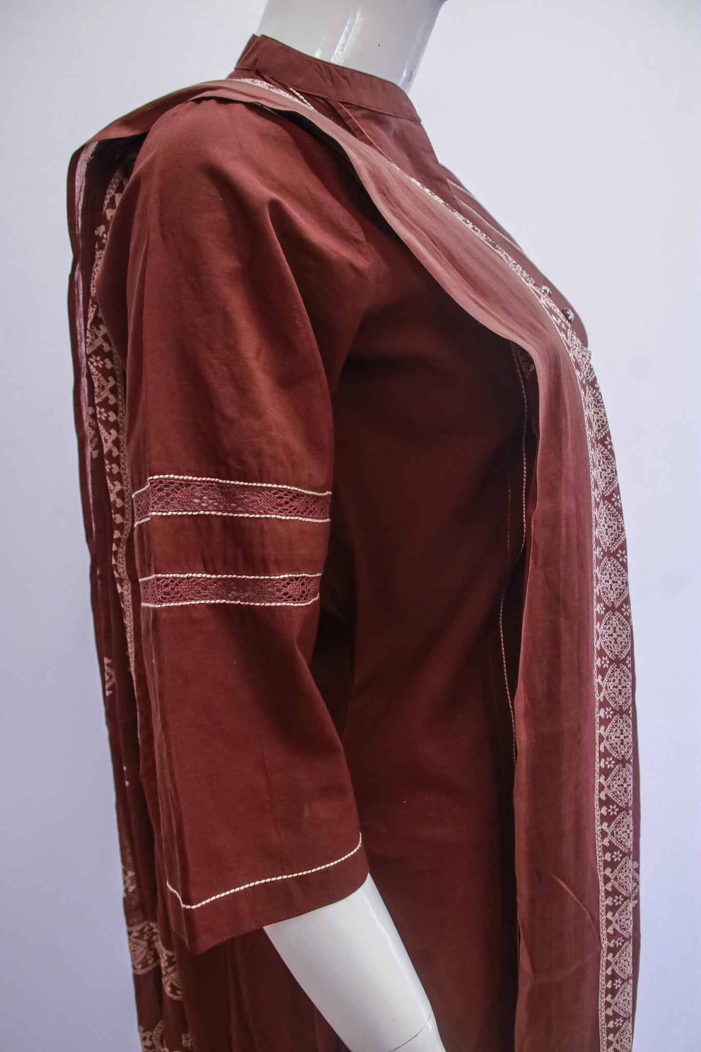 Brown traditional outfit with intricate patterns on a mannequin against a white background