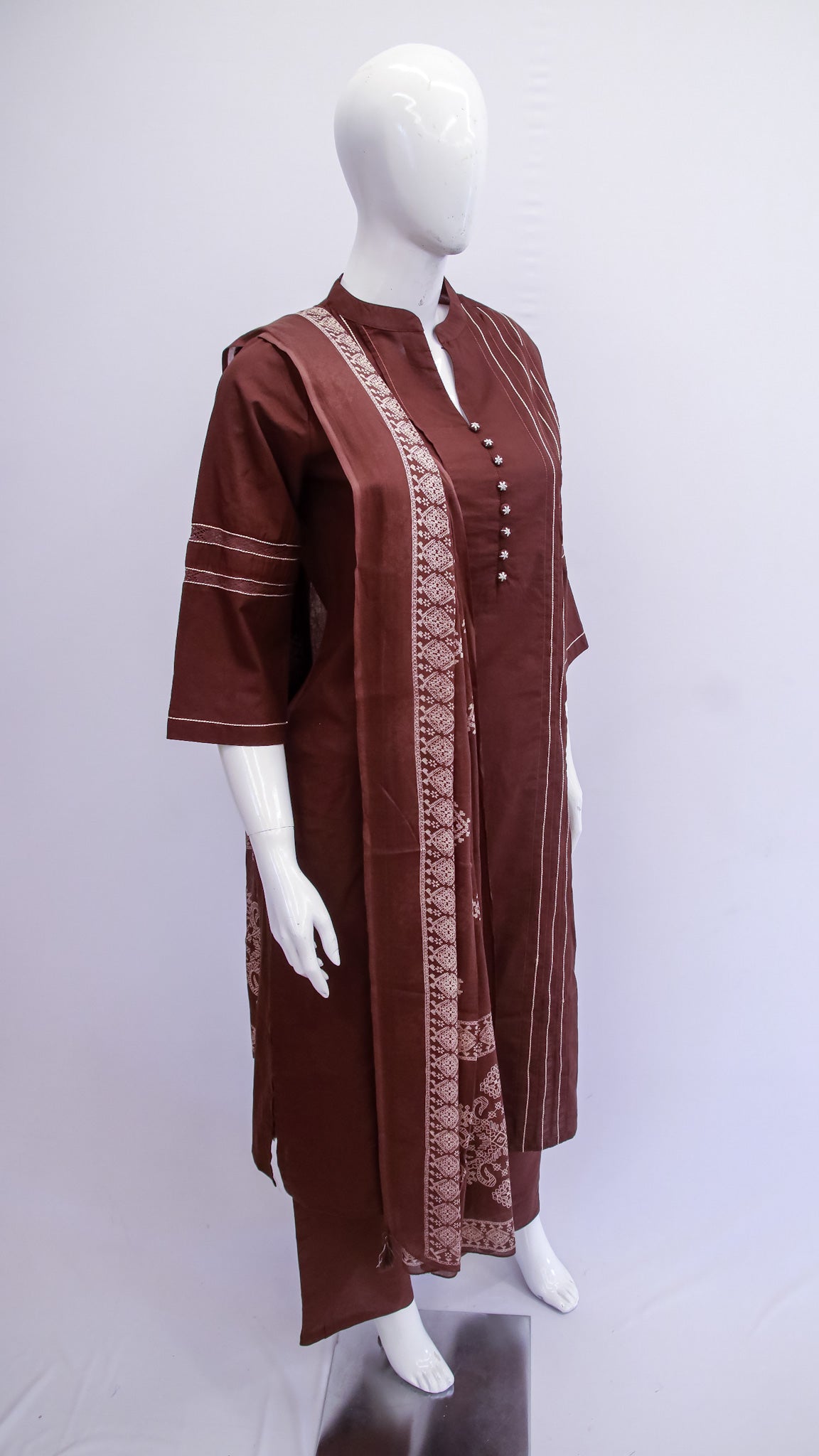 Brown traditional outfit with intricate patterns on a mannequin against a white background