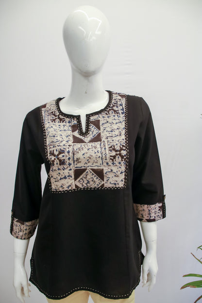 Black blouse with patterned neckline on a mannequin against a white background