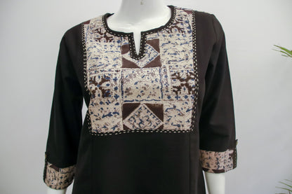 Black long-sleeve top with patterned patchwork design on a mannequin against a white background