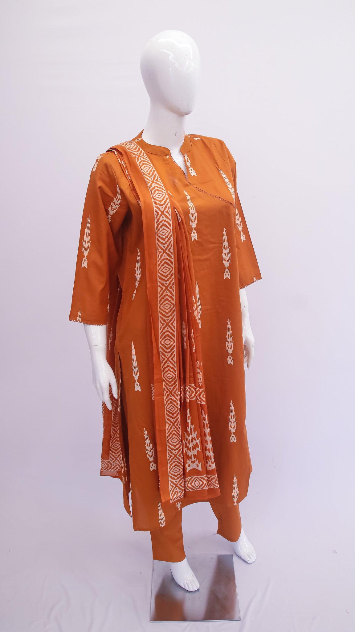Orange kurta with white patterns on a mannequin against a white background