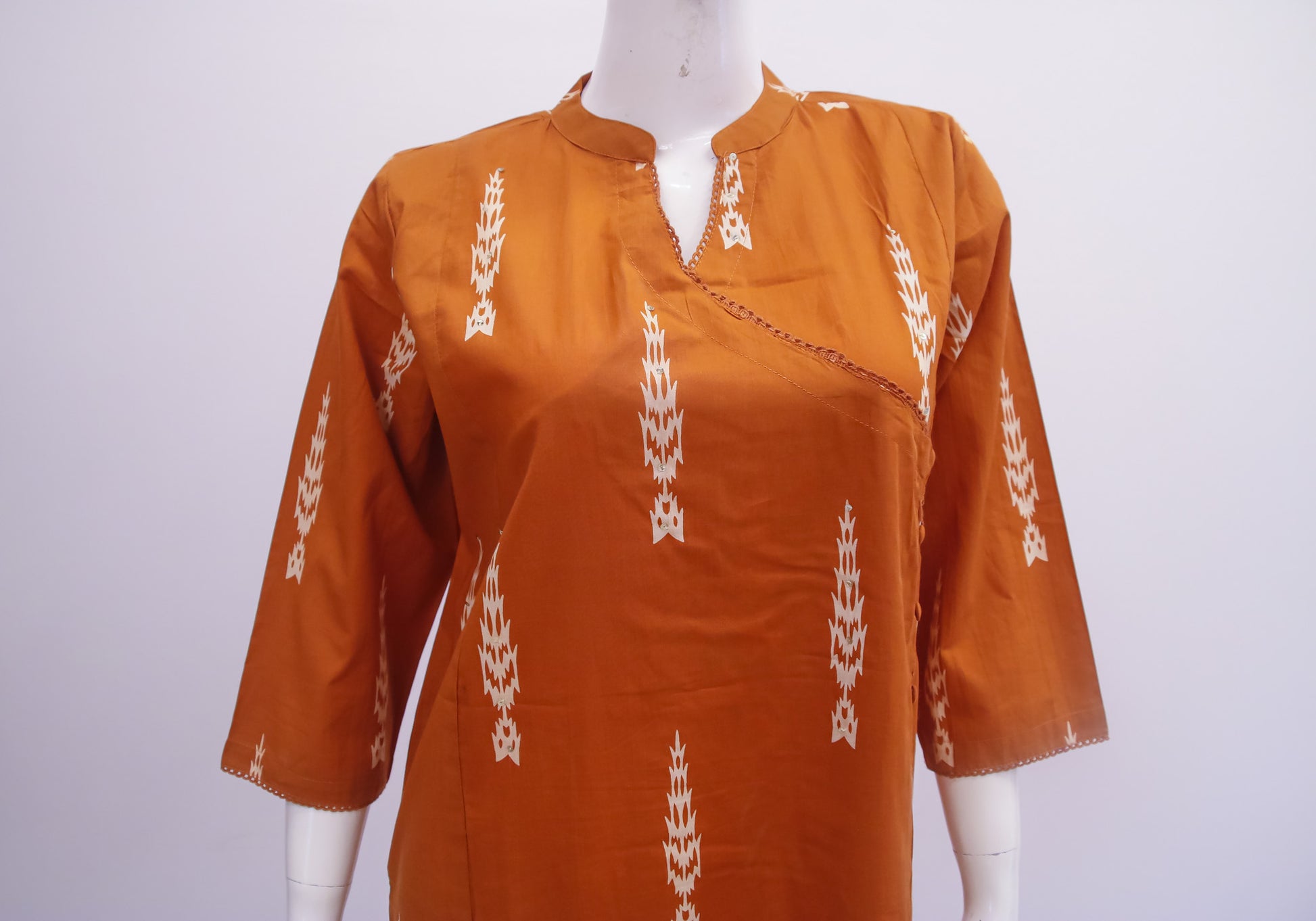 Brown kurta with white patterns on a mannequin against a white background