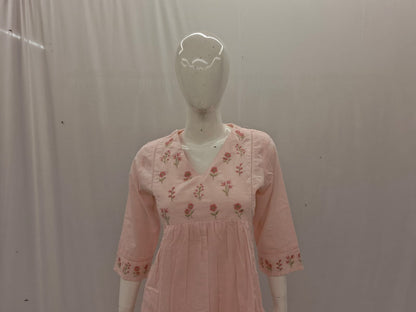 Mannequin wearing a pink dress with floral embroidery against a plain background
