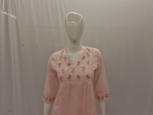 Mannequin wearing a pink dress with floral embroidery against a plain background
