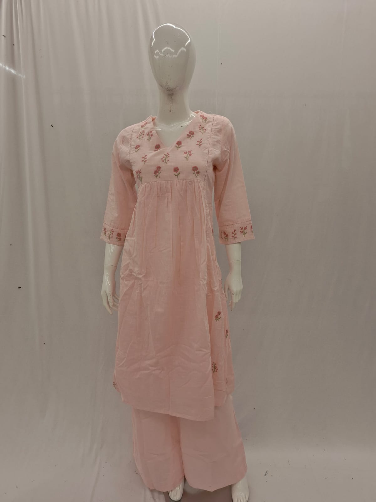 Mannequin wearing a pink traditional outfit with floral embroidery on a plain background